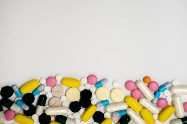 Kapsüllerdeki uyuşturucu yığını ve beyaz arka plandaki farklı renklerdeki haplar