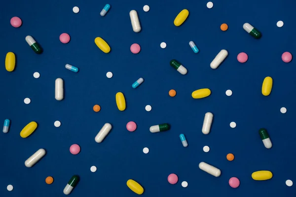 Modré Pozadí Mnoha Léky Kapslích Tabletách Různých Barev Rozptýlených Povrchu — Stock fotografie