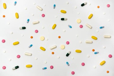 Kapsüllerdeki uyuşturucuların çeşitliliği ve beyaz arka plandaki farklı renklerdeki haplar