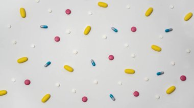 Kapsüllerdeki uyuşturucuların çeşitliliği ve beyaz arka plandaki farklı renklerdeki haplar