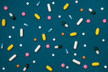 Kapsül ve tabletlerde bulunan mavi arka plan yüzeye dağılmış farklı renklerde