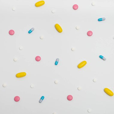 Kapsüllerdeki uyuşturucuların çeşitliliği ve beyaz arka plandaki farklı renklerdeki haplar