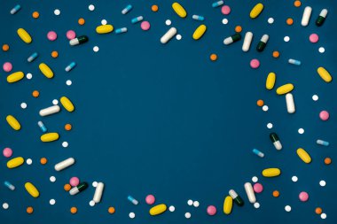 Fotokopi alanı olan mavi arkaplan ve kapsül ve tabletlerde yüzeye dağılmış birçok farklı renk içeren uyuşturucular