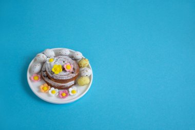 Mavi arka planda yumurta ve şeker çiçekli Paskalya desenli çörekler.
