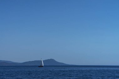 Mavi sisli adaların arka planına karşı denizde beyaz yelkenli bir gemi ya da yat. Zengin yaşam konsepti. Romantik.