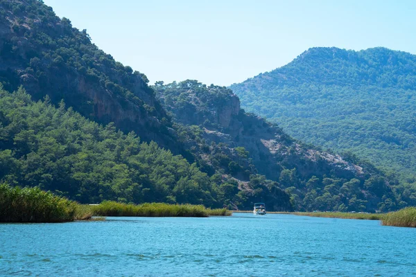 Türkiye 'nin güneybatı kıyısındaki Marmaris ve Fethiye ilçeleri arasında yer alan Mugla ilindeki Lycian mezarlarının bulunduğu kayaların yanındaki Dalyan Nehri' nde turistik gezi teknesi.