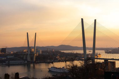 Güneş batarken veya gün doğarken Altın Boynuz Boğazı 'ndan geçen kablo destekli köprü, Vladivostok, Primorsky Krai, Rusya.