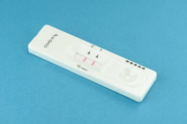 Mavi arkaplan üzerinde pozitif antijen covid-19 testinin yakın görüntüsü