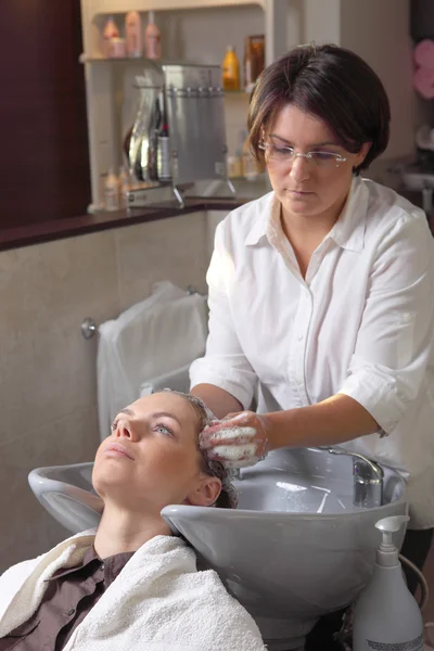 Hermosa joven disfrutando del lavado de cabello en el salón de peluquería — Foto de Stock