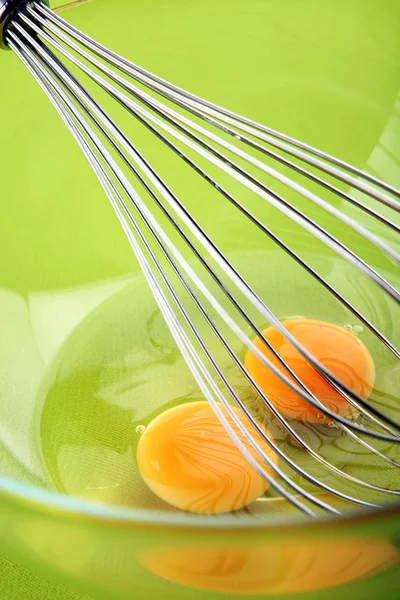 Ruční mixer s vejci ve skleněné mísy na zeleném pozadí — Stock fotografie