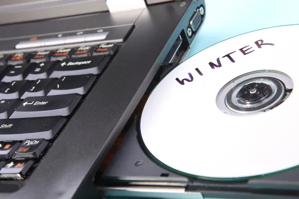 Immagine ravvicinata di un computer portatile e di un disco CD o DVD — Foto Stock