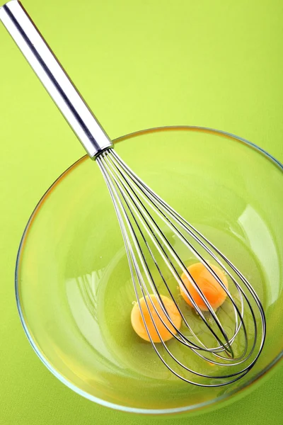 Mikser ręczny z jaj w misce szkła na zielonym tle — Zdjęcie stockowe