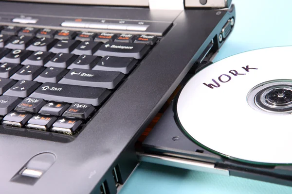 Immagine ravvicinata di un computer portatile e di un disco CD o DVD — Foto Stock