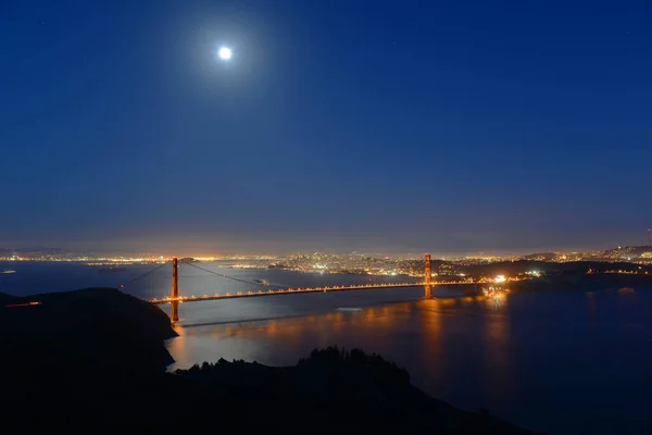 Golden Gate Bridge at full moon night, with San Francisco city skyline at back ground, San Francisco, California CA, USA.