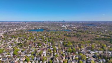 Arlington Heights suburban landscape aerial view in spring with Spy Pond and Boston modern city skyline at the background in historic town of Arlington, Massachusetts MA, USA. 