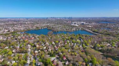 Arlington Heights suburban landscape aerial view in spring with Spy Pond and Boston modern city skyline at the background in historic town of Arlington, Massachusetts MA, USA. 