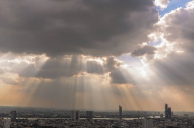 Bangkok, Tayland - 03 Kasım 2020: Güneş ışınları bulutların arasından geçiyor ve Bangkok şehrinin manzarası üzerinden gökyüzünde parlıyor. Boşluğu kopyala, Seçici odak.