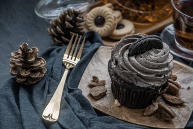 Koyu mavi kumaşlı bir fincan meyveli çayla Orio keki. Yukarıdan belirsiz görünüm.