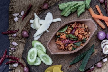 Kızarmış kaffir limon yapraklı domuz eti ezmesi ve ahşap arka planda taze sebzeler..