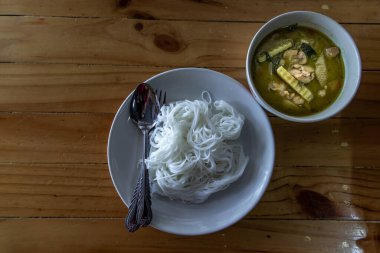 Tayland mutfağı seti, baharatlı yeşil köri tavuğu ahşap masada pirinç vermicelli ile servis edilir, çok ünlü Tayland mutfağı, yukarıdan manzara, seçici odak.