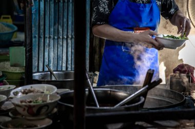 Bangkok, Tayland - 27 Ekim 2019: Tayland sokak yemeklerinde aşçı kızarmış domuz etli erişte pişiriyor. Geleneksel Asya yemeklerinde erişte yapmak. Çin yumurtalı erişte ve haşlanmış çorba, seçici odaklanma..