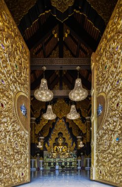 Lampang, Thailand - Sep 04, 2019 : Looking through the beautiful architecture temple door of The golden buddha image within Wat Phra That Doi Phra Chan in Lampang. A temple on the top of a mountain the north of thailand. Selective focus. clipart
