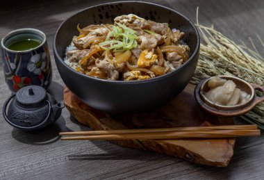 Japon domuz pirinci kasesi yumurta ve soğanlı (Donburi) turşulu zencefil ve ahşap masada yeşil çay ile servis edilir. Japon yemek tarzı..