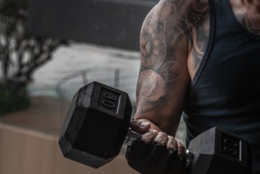 Bangkok, Tayland 06 Ekim 2019: Güçlü vücut geliştirici, spor salonunda ya da fitness kulübünde halterle kas pompalayan güçlü atletik adam.