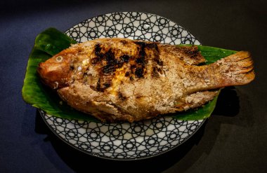Tilapia balık güzel bir tabakta muz yaprağı üzerinde ızgara, Tay gıdalar tarzı yerleştirilir, üstten eğik görünümü.