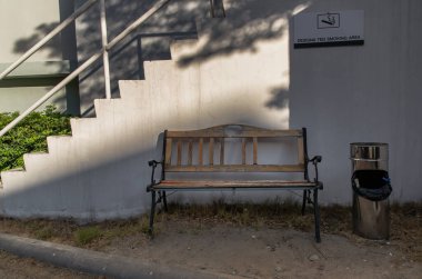 Sigara içme alanı: Üzerinde sigara içme alanı işareti olan sigara içenler için kül tablası olan ahşap bank. Tam olarak odaklanamıyorum..