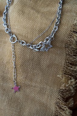 Gümüş mücevher fotoğrafçılığı. Gümüş kolye moda fotoğrafçılığı. Kahverengi çuval bezinde sunulan kolye. Kadın aksesuarları. Odaklan ve bulanık.