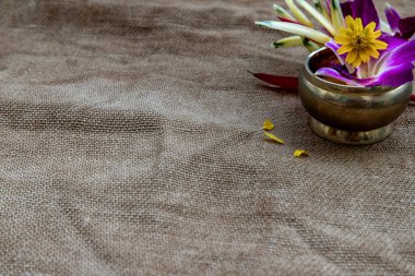 Köşedeki pirinç bardaklarda çiçekler çuval bezi arka planda, arkaplanın sağ üst köşesinde metin veya mesajınız için hazır, boşluğu kopyala.