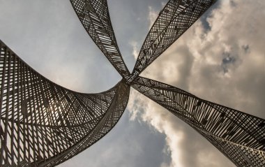 Bangkok, Tayland - 20 Mayıs 2021: Parkta dekoratif çekicilik için altın çelik heykel. Mimari yapı dekoratif metalden oluşur, arka planda mavi bir gökyüzüne karşı alçak bir açıdan çekilir. Seçici odak.