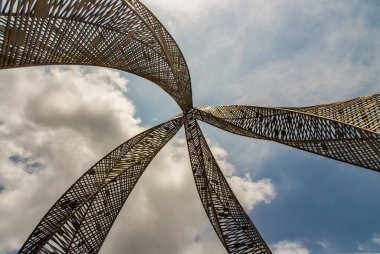 Bangkok, Tayland - 20 Mayıs 2021: Parkta dekoratif çekicilik için altın çelik heykel. Mimari yapı dekoratif metalden oluşur, arka planda mavi bir gökyüzüne karşı alçak bir açıdan çekilir. Seçici odak.