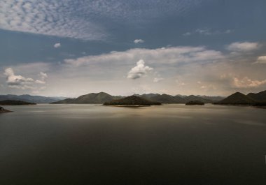 Gün doğumunda veya günbatımında arkaplanda dağlar olan göl kıyısı manzarası. Odaklan ve bulanık.