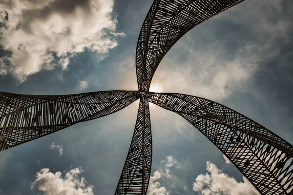 Bangkok, Tayland - 20 Mayıs 2021: Parkta dekoratif çekicilik için altın çelik heykel. Mimari yapı dekoratif metalden oluşur, arka planda mavi bir gökyüzüne karşı alçak bir açıdan çekilir. Odaklan ve bulanık.