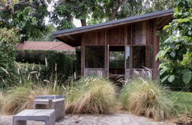 Nice small wooden hut. Green garden joy in summer with Stone benchs and perennial ryegrass plant. Relax in the garden and enjoy the beautiful weather. Selective focus.