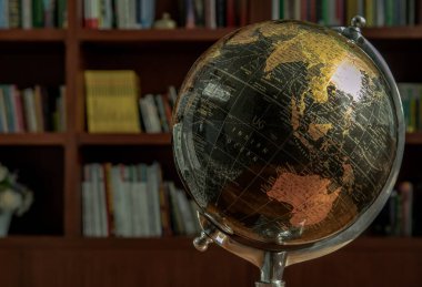 Chiang Rai,Thailand - Sep 06, 2020 : Replica globe on the background of bookshelves in library with copy space. No focus, specifically.