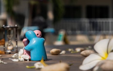 Mavi ve pembe seramik bebekler taş arka planda birbirlerine sarılırlar. Yıldönümü, evlilik ve sonsuz aşk kavramı, romantik düğün veya sevgililer günü kavramı.