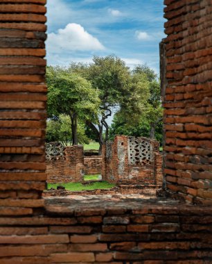 Kırmızı tuğla duvardan yeşil ağaçlara ve Ayuthaya 'daki eski tapınağın kalıntılarına bakıyorum. Tam olarak odaklanamıyorum..