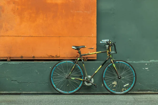 Ένα Ποδήλατο Μπροστά Από Ατσάλινη Πορτοκαλί Πόρτα Πράσινο Τοίχο Της — Φωτογραφία Αρχείου