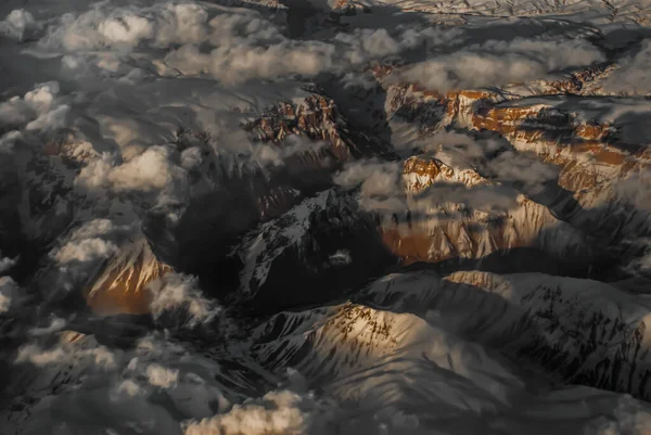 Widok Samolotu Wzgórz Śnieg Krajobraz Gór Cieniami Światła Słonecznego Chmury — Zdjęcie stockowe