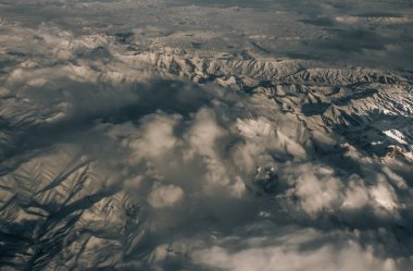 Tepeler düzleminden gökyüzü manzarası. Kar ve dağlar. Güneş ışığı gölgeleri ve bulutlar güzel bir şekilde örtülmüş. Bulutların üstünde, dağların tepesinde, odaklanmadan, özellikle..