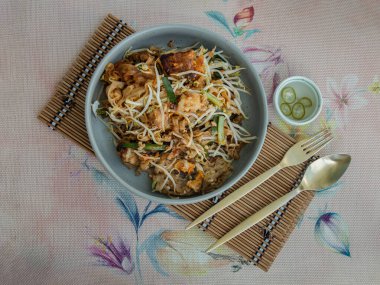 Kızarmış Tayland eriştesi (pad thai) karışık şalgam keki (chai tow kway) ile fasulye filizi ve kırmızı biberli soğan. Seçici odak.