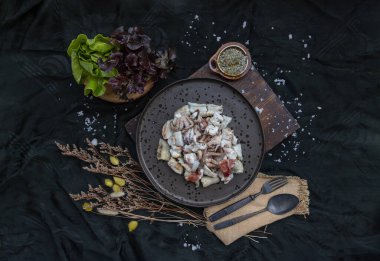 Taze ızgara kalamar, ahtapot dokunaçları ve seramik tabakta taze sebze ve baharatlı deniz ürünleri sosuyla servis edilen kalamar yumurtaları. Üst Görünüm, Seçici Odaklanma.