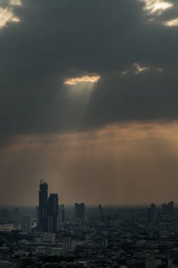 Güneş ışınları bulutların arasından geçiyor ve Bangkok 'un gökdeleninden kayarak iniyor. Bulutlara seçici odaklanma.