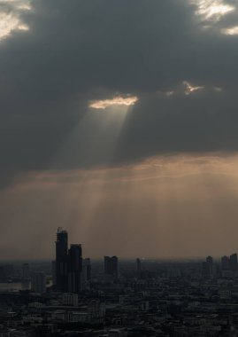 Güneş ışınları bulutların arasından geçiyor ve Bangkok 'un gökdeleninden kayarak iniyor. Delik aydınlatma seçimi.