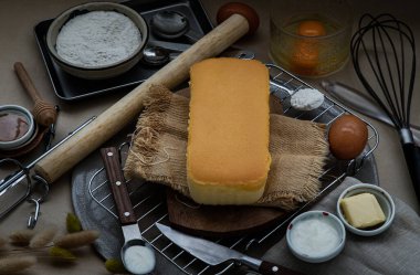 Ev yapımı tereyağlı kek (yumurta, un, süt, ballı tereyağı) ve açık kahverengi masada çırpılmış yumurta. Seçici odak.