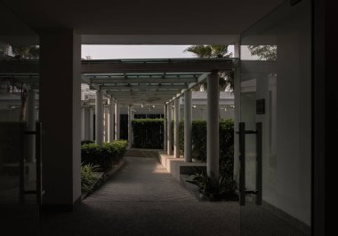 Bangkok, Tayland - 14 Nisan 2022: Yapının çatısı ve tavanı cam ve çelikten yapılmıştır. Taş zemin manzarası ve bahçenin dış yoluna çıkan beyaz beton sütunlar. Simetri ve geometri, Seçici odak.