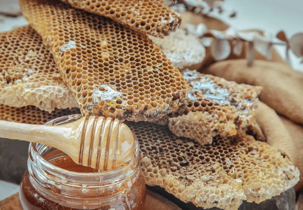 Ballı kavanoza ballı şeker çubuğu yapıştırılmış taze bal petekleri. Sağlıklı organik natura, bal, metin için boşluk, seçici odak.